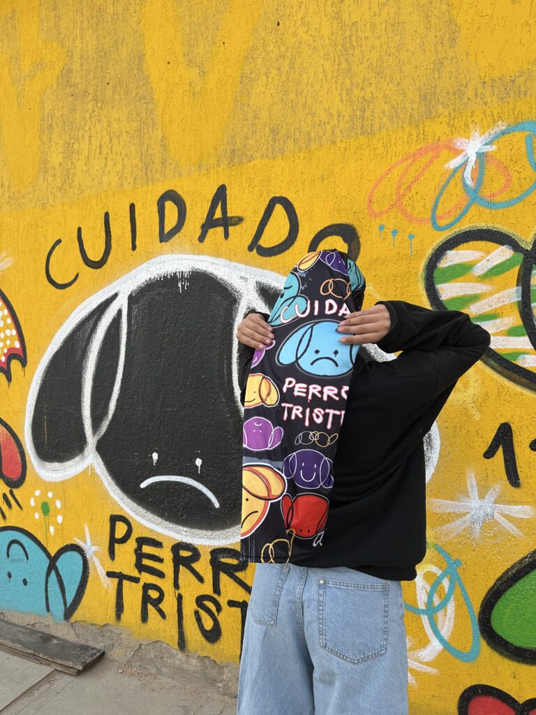 Modelo con cuello edición limitada Cuidado Perro Triste frente al mural original en colaboración con Los Cuellos del Mono